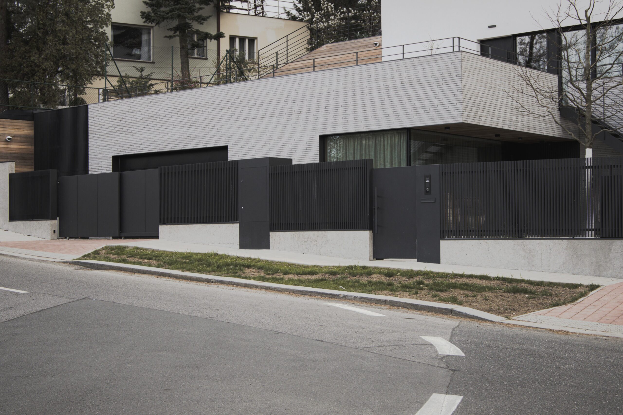 PROWERK exklusivní vstupní oplocení RD Praha. Součást oplocení teleskopické brány, vstupní branka s funkčním sloupkem, opláštění pilířku v designu FORTIS PV1404 - plechové 2D panely. Plotová pole v designu MIRAGE PV1602 se svislými předsazenými mikro-lamelami slícovanými s podezdívkou.