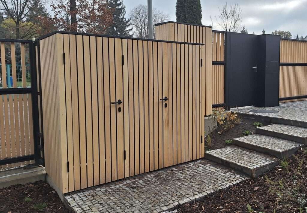 Skříň s boxem pro tři popelnice 240l jako součást oplocení. Trojité dveře na vnitřní i vnější straně. Obložení dřevem